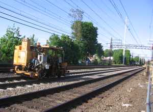 A ballast tamping machine on track 3 at East Norwalk station.  Other maintainence of way equipment is visible further down the line looking east.