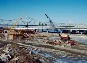 Looking NW from near what will later be the intersection of Witherspoon St. and Bingham Way.
Witherspoon St. parking garage under construction.
I-64 and Clark Bridge in distance.
Ohio River mile 604.
Louisville, Kentucky.
January 1988.
File #