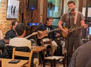 Open mic at The Local on 824 Hinton Avenue in the Belmont neighborhood of Charlottesville, Virginia. Michael Clem and Brennan Gilmore play guitar behind performer.