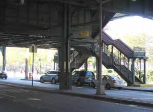 Looking north across Brighton Avenue, underneath the Brighton Line at en:Ocean Parkway (BMT Brighton Line) station stair on a sunny afternoon